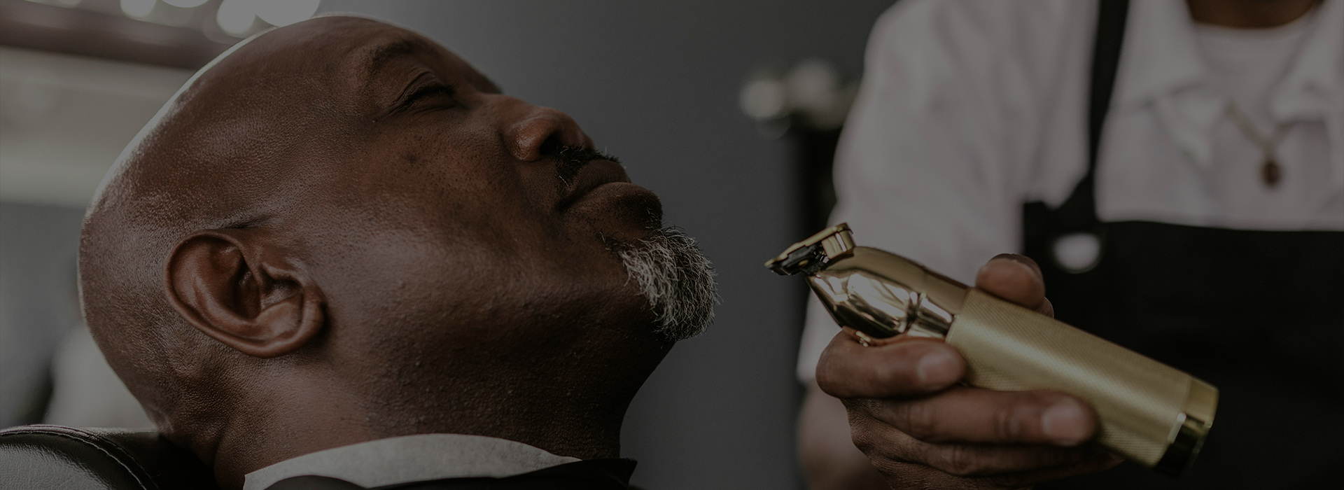 Barber trimming a client's beard with clippers