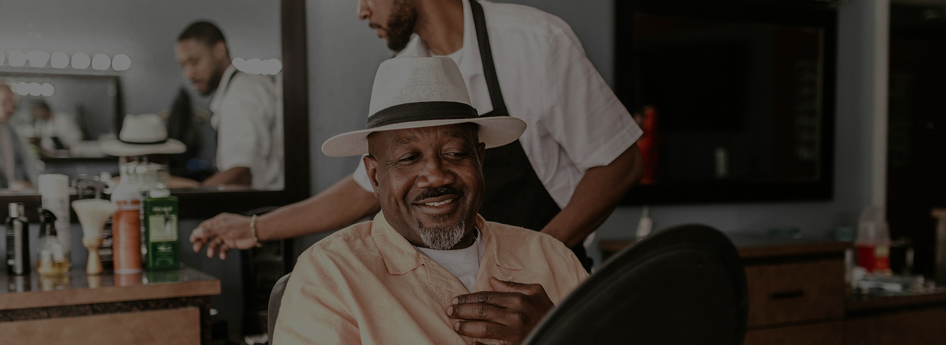 Smiling client in a hat getting a haircut